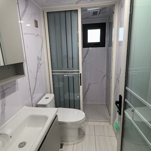 Modern bathroom with toilet, sink, and enclosed shower.