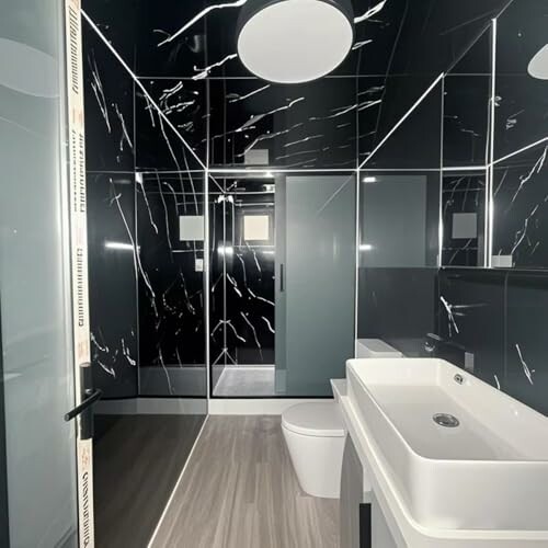 Modern bathroom with black marble walls and sleek fixtures.
