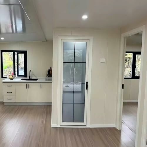 Modern kitchen with a sink and a glass door leading to another room.