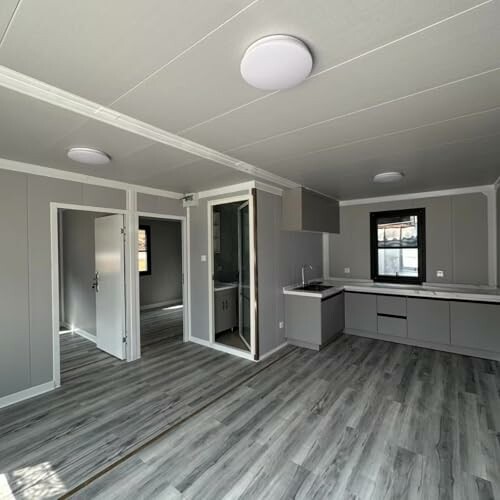 Modern kitchen and living area with gray flooring and white walls.