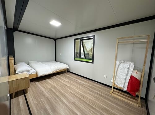 Minimalist bedroom with wooden flooring, bed, window, and open wardrobe.