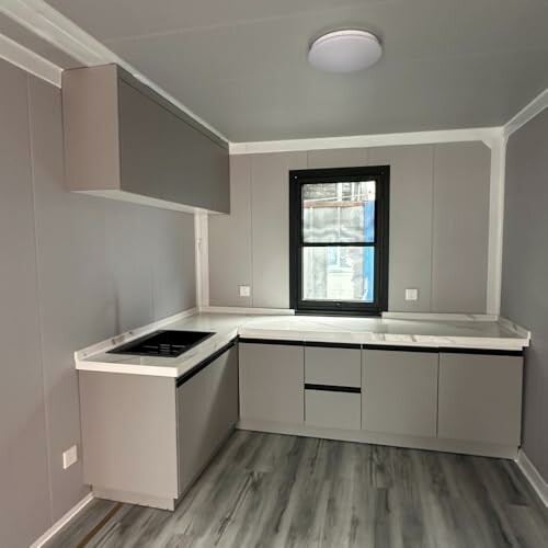 Modern minimalist kitchen with gray cabinets and wooden floor.