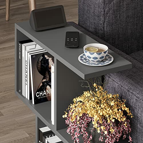 Shelf with books, teacup, remote, and decorative plant.