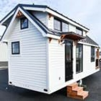 A modern tiny house on wheels with white siding and black trim.