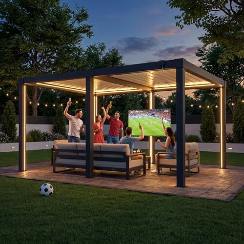 Group of people watching a soccer game on an outdoor TV under a lit pergola.