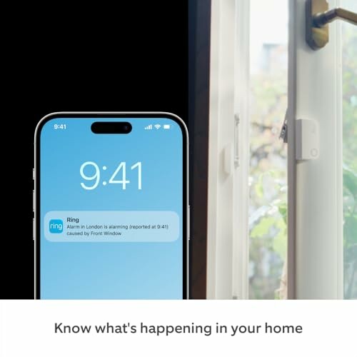 Smartphone displaying home security alert next to open window sensor.