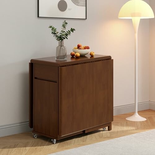 Wooden folding table with a plant and fruit bowl on top.